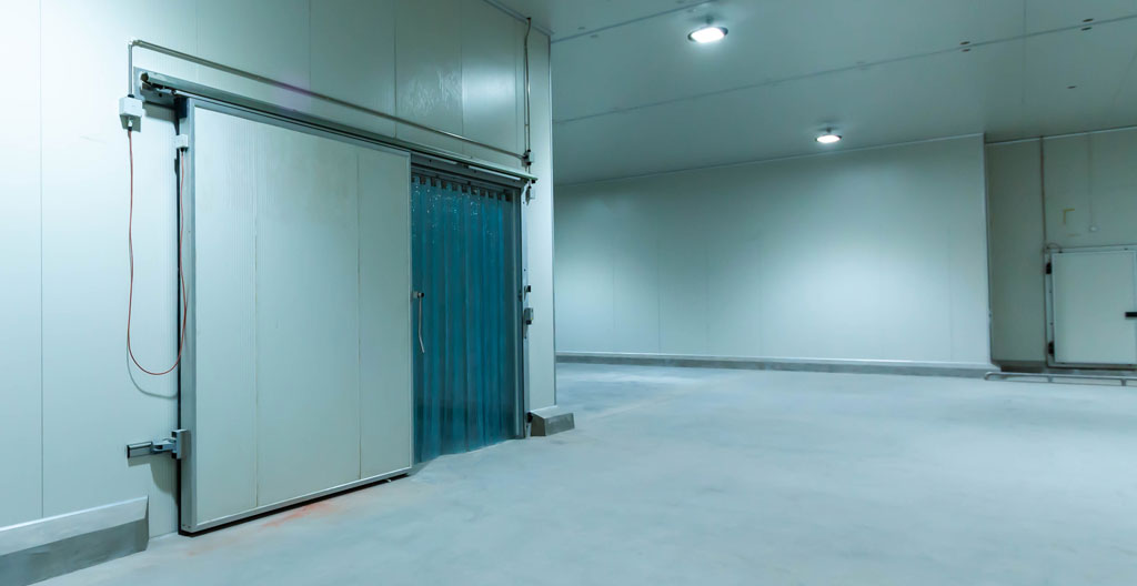Chambre froide avec porte sectionnelle ouverte montrant la condensation et les échanges thermiques